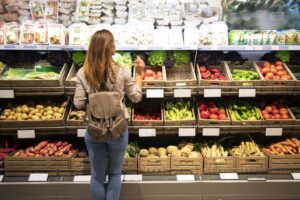 good-looking-woman-standing-front-vegetable-shelves-choosing-what-buy-min